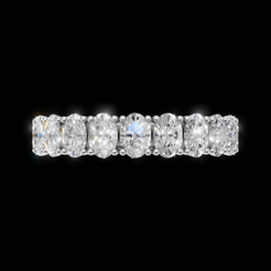 A diamond eternity band ring featuring six oval-cut diamonds set in a silver-colored metal, shown against a solid black background.
